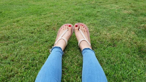 Füße-Selfie in goldenen Sandalen auf grünem Gras-Hintergrund — Stockfoto