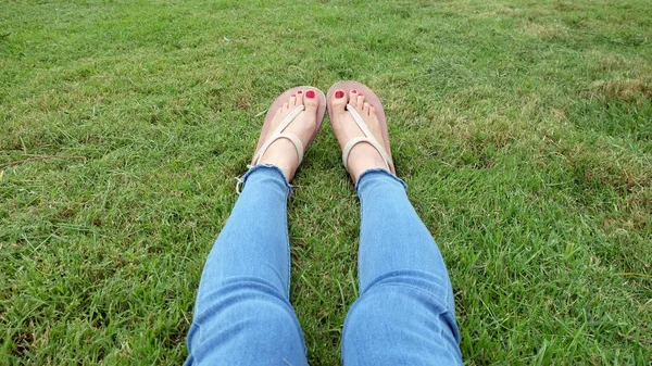 站在绿草背景上的金凉鞋中的脚自拍 — 图库照片