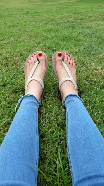 Pieds Selfie dans des sandales en or debout sur fond d'herbe verte — Photo