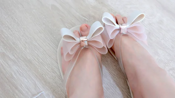 Fötter av kvinnor bära Nude platta sandaler med rosett söt på en trä bakgrund — Stockfoto