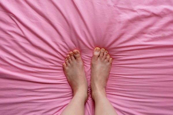 Крупним планом жіночих ніг і тонкий ноги на рожевий ліжко, ноги у фоновому режимі спальні будинку — стокове фото