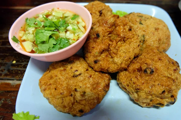 Bolas de pasta de pescado frito con hierbas y salsa, comida tailandesa en plato azul en mesa de madera — Foto de Stock
