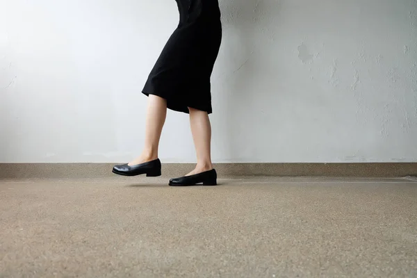Γυναίκα Slim τα πόδια φορούν μαύρο φόρεμα και μαύρα παπούτσια στο δρόμο φόντο — Φωτογραφία Αρχείου