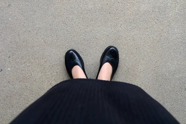 Szczupłe nogi kobiety nosić czarny strój i czarne buty na ulicy tle — Zdjęcie stockowe