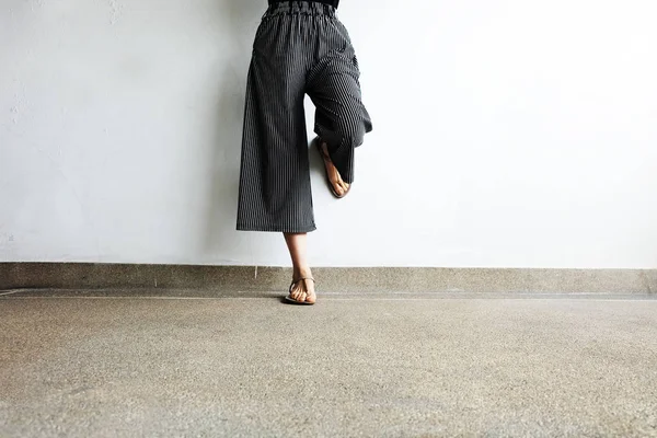 脚的女人穿凉鞋和黑色的裤子。女性站在水泥背景 — 图库照片