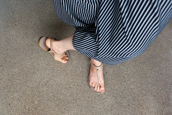 Pés de mulher usam sandálias e calças pretas. Feminino em pé no fundo do cimento — Fotografia de Stock