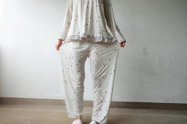 Kız pijama ve kat arka plan üzerinde beyaz terlik ayakta