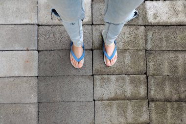 Genç kadın bacakları mavi sandalet ve Mavi Jeans. Çimento arka plan üzerinde duran erkek