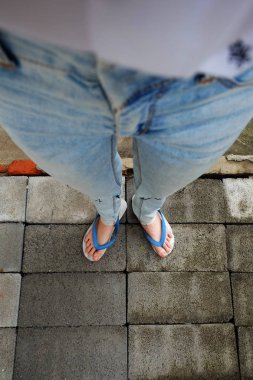 Genç kadın bacakları mavi sandalet ve Mavi Jeans. Çimento arka plan üzerinde duran erkek