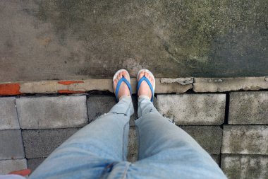 Genç kadın bacakları mavi sandalet ve Mavi Jeans. Çimento arka plan üzerinde duran erkek