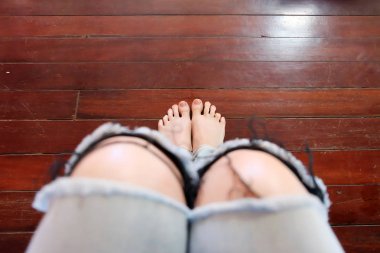 Close Up Woman Barefoot Wear Blue Jeans on Wooden Floor Background clipart