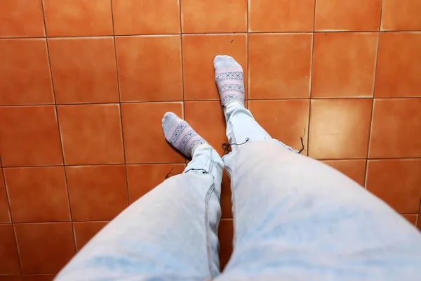 Close Up Woman's Feet Wear Socks and Blue Jeans on Brown Tile Background