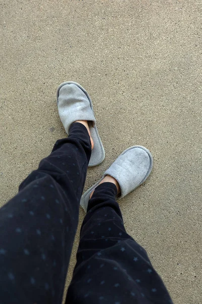 Nahaufnahme von Frauenfüßen tragen graue Hausschuhe auf dem Zementhintergrund — Stockfoto