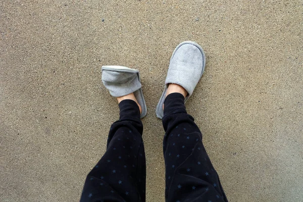 Закрыть ноги женщины в серых тапочках на цементном фоне — стоковое фото