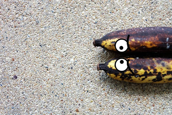 Μπανάνα - σάπιο μπανάνες με τα μάτια στο σκυρόδεμα φόντο — Φωτογραφία Αρχείου