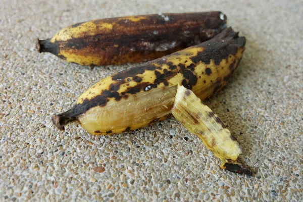 Húzza a banán, két régi fekete romlott banán gyümölcs beton alapon — Stock Fotó