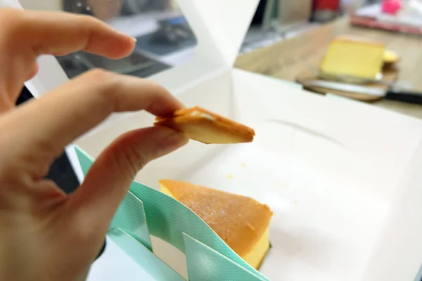 Nahaufnahme quadratisches Brot, Hand halten Cracker auf Schachtel Kuchen Hintergrund — Stockfoto