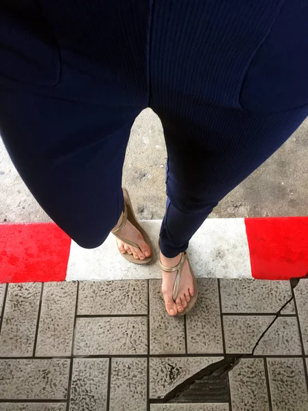 Pés Femininos usam sandálias de pé vermelho e branco fio de concreto, estrada de concreto - calçada para fundo — Fotografia de Stock