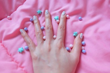 Granit gri çivi. Pembe battaniye arka plan üzerinde renkli boncuk boyasıyla çivi kadar kapatın