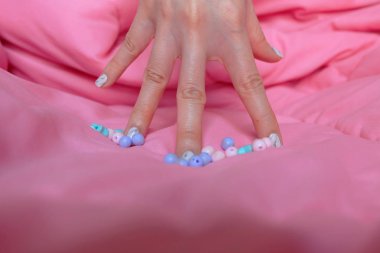 Granit gri çivi. Pembe battaniye arka plan üzerinde renkli boncuk boyasıyla çivi kadar kapatın