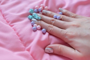 Granit gri çivi. Pembe battaniye arka plan üzerinde renkli boncuk boyasıyla çivi kadar kapatın