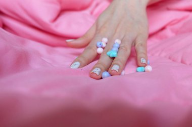 Granit gri çivi. Pembe battaniye arka plan üzerinde renkli boncuk boyasıyla çivi kadar kapatın