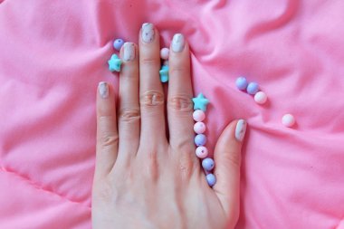 Granit gri çivi. Pembe battaniye arka plan üzerinde renkli boncuk boyasıyla çivi kadar kapatın