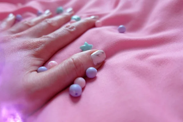 Uña de granito gris. Esmalte de uñas de cerca con cuentas de colores sobre fondo de manta rosa — Foto de Stock