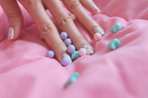 Granitgrauer Nagel. Nahaufnahme Nagellack mit bunten Perlen auf rosa Decke Hintergrund — Stockfoto