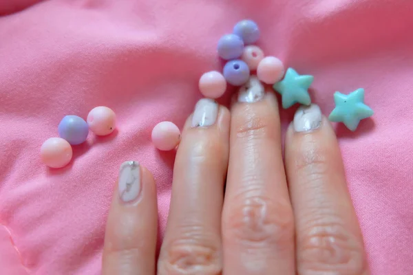 Granit gri çivi. Pembe battaniye arka plan üzerinde renkli boncuk boyasıyla çivi kadar kapatın