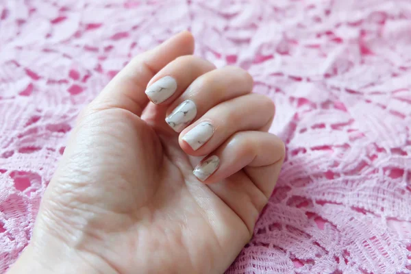 Unghie belle, chiodi manicure donna da vicino e mani su sfondo tessuto rosa — Foto Stock