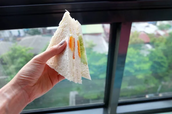 Close Up Mulher mão segurando sanduíche com ovo em vista de fundo — Fotografia de Stock