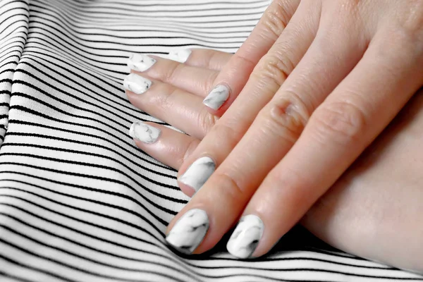 Esmalte de uñas y manicura. Cerca de uñas de granito gris con fondo de tela en blanco y negro — Foto de Stock