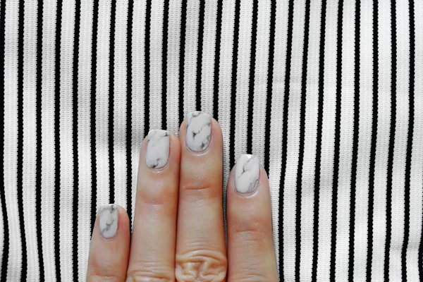 Smalto per mani e unghie, Manicure. Chiodi grigio granito da vicino con sfondo in tessuto bianco e nero — Foto Stock