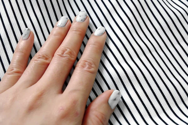 Rąk i paznokci, Manicure paznokci. Zbliżenie granit szary paznokcie z czerni i bieli tkanina tło — Zdjęcie stockowe
