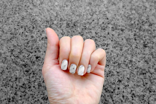 Esmalte de uñas y manicura. Primer plano uñas de granito gris sobre fondo de granito — Foto de Stock