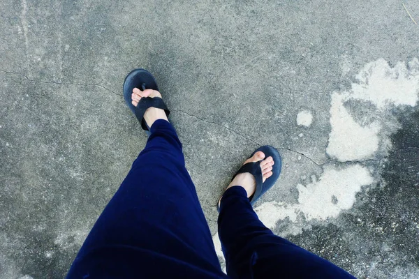 Sandalia de mujer. Selfie de Pies en Sandalias Negras con Pantalones Azules De Pie Sobre El Fondo Del Suelo —  Fotos de Stock