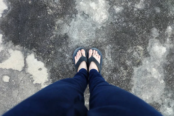 Sandália de Mulher. Pés Selfie em sandálias pretas com calças azuis em pé no fundo do chão — Fotografia de Stock
