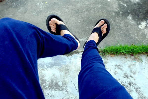 Sandalia de mujer. Selfie de Pies en Sandalias Negras con Pantalones Azules De Pie Sobre El Fondo Del Suelo —  Fotos de Stock