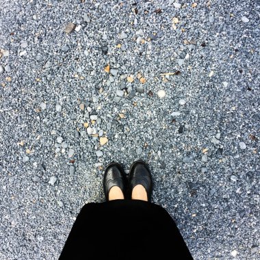 Siyah sandalet giyen kadın ayakları üzerinde yakın çekim ve elbise, duran bir taş üzerinde anmak