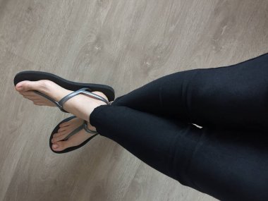 Siyah sandalet giyen kadın ayağa kadar yakın ve kot ahşap arka plan üzerinde siyah