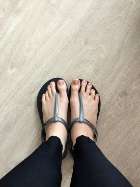 Siyah sandalet giyen kadın ayağa kadar yakın ve kot ahşap arka plan üzerinde siyah