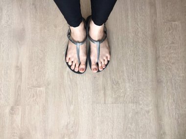 Siyah sandalet giyen kadın ayağa kadar yakın ve kot ahşap arka plan üzerinde siyah