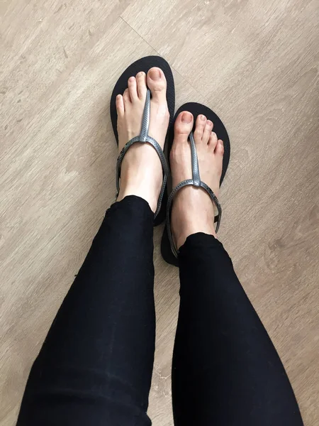 Siyah sandalet giyen kadın ayağa kadar yakın ve kot ahşap arka plan üzerinde siyah