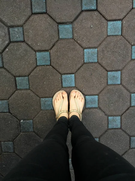 Selfie kvinnans fötter bär sandaler och svarta Jeans på bildrutsbakgrund — Stockfoto