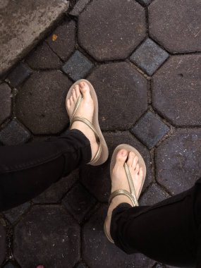 Sandalet ve siyah kot giyen döşeme arka planı üzerinde Selfie kadının ayak