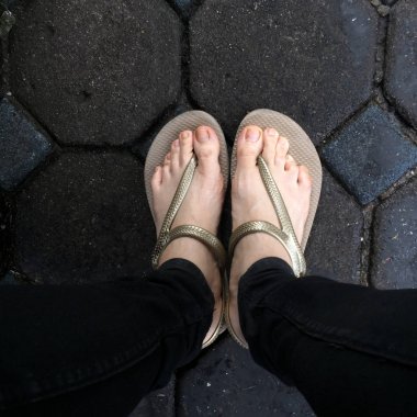 Sandalet ve siyah kot giyen döşeme arka planı üzerinde Selfie kadının ayak