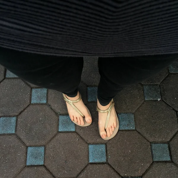 Pés de mulher selfie vestindo sandálias e calças de ganga pretas no fundo da telha — Fotografia de Stock