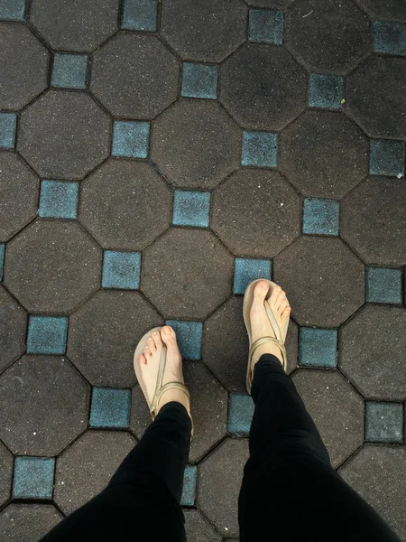 Pies de mujer selfie con sandalias y pantalones vaqueros negros en el fondo del azulejo —  Fotos de Stock