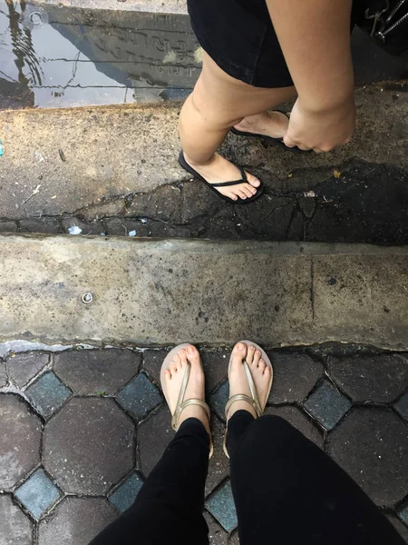 Pés de mulher selfie vestindo sandálias e calças de ganga pretas no fundo da telha — Fotografia de Stock